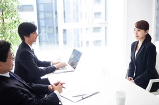 中小企業のオフィスでノートパソコンに向かう社員